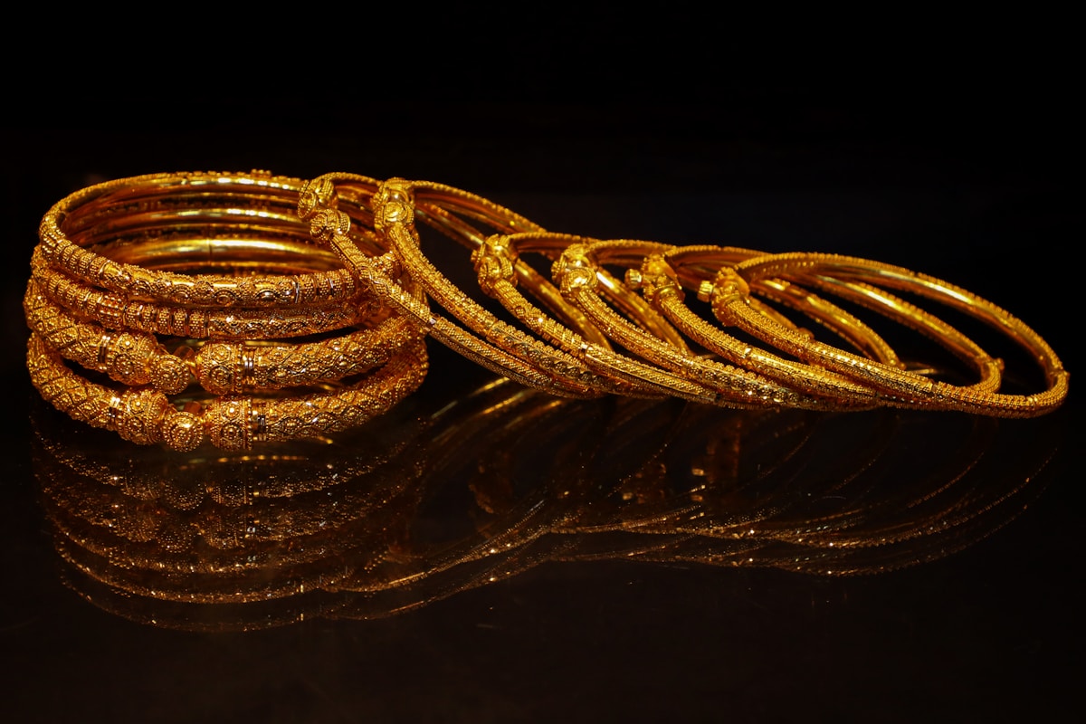 A stack of ornate gold bangles on a dark surface.