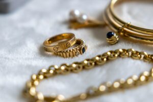"Bijoux de luxe dorés disposés sur une surface blanche douce, conseils pour comment entretenir ses bijoux de luxe."