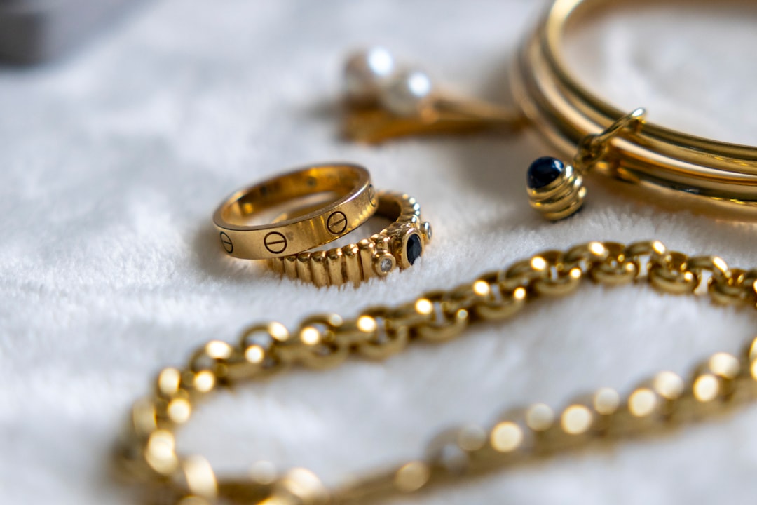 "Bijoux de luxe dorés disposés sur une surface blanche douce, conseils pour comment entretenir ses bijoux de luxe."