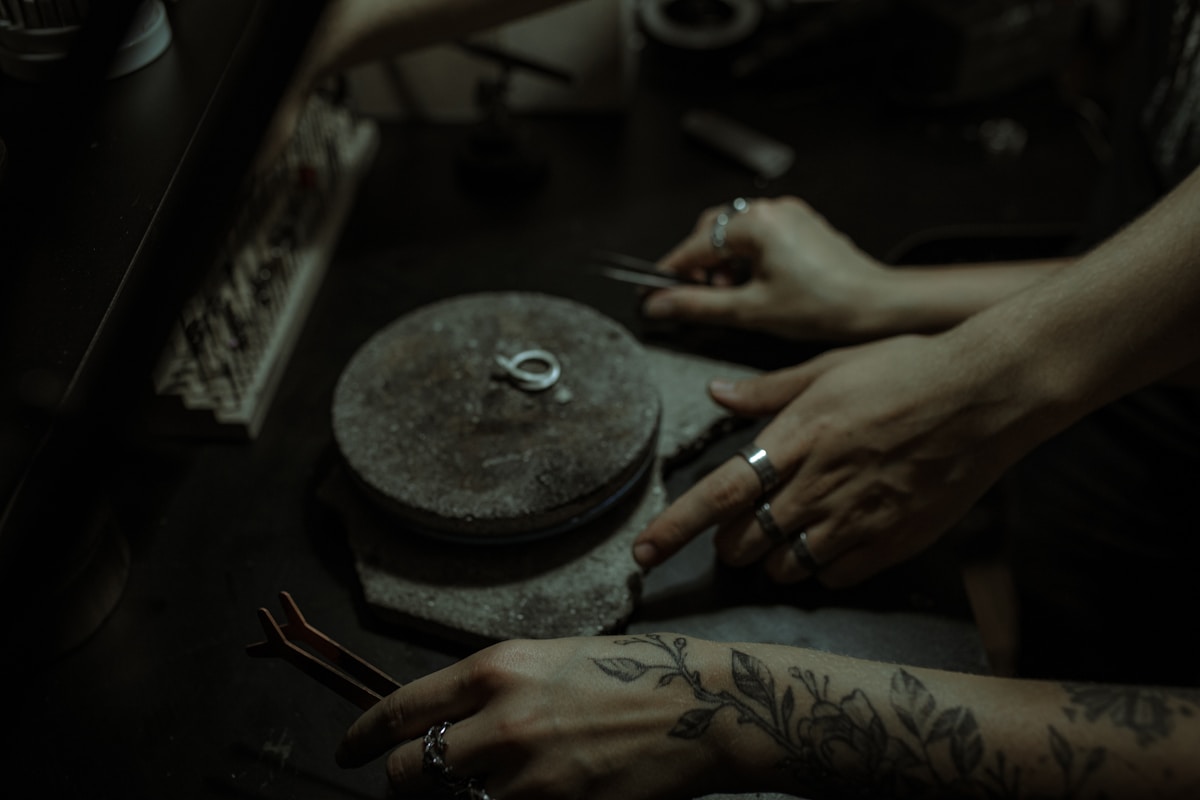 Mains tatouées travaillant sur un outil de meulage sombre.