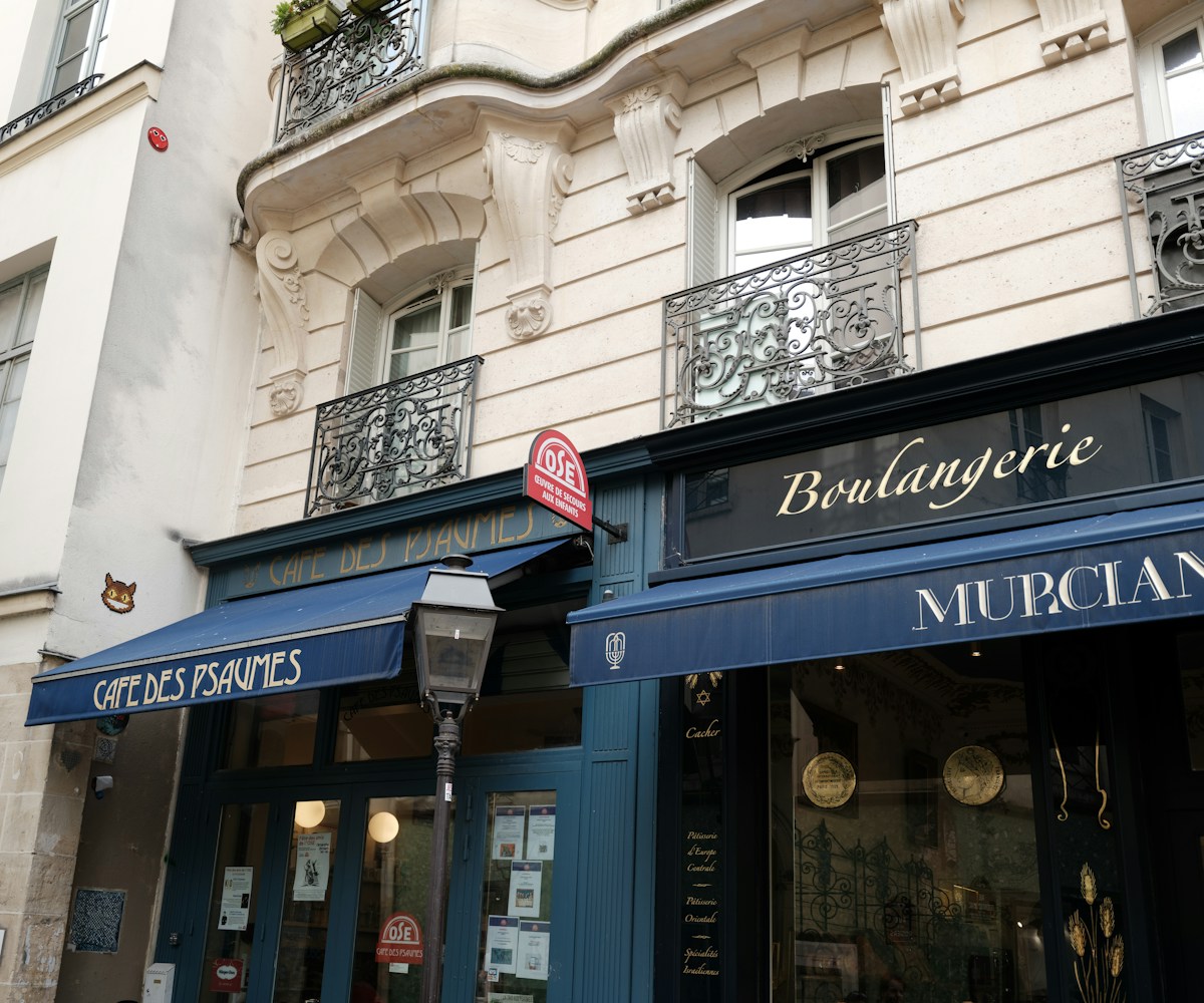 Façade ornementée d'un immeuble parisien avec boulangerie et café.