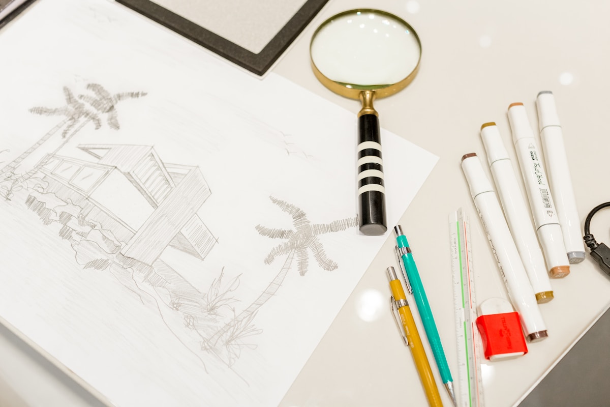 Esquisse artistique avec outils de dessin et loupe sur table.