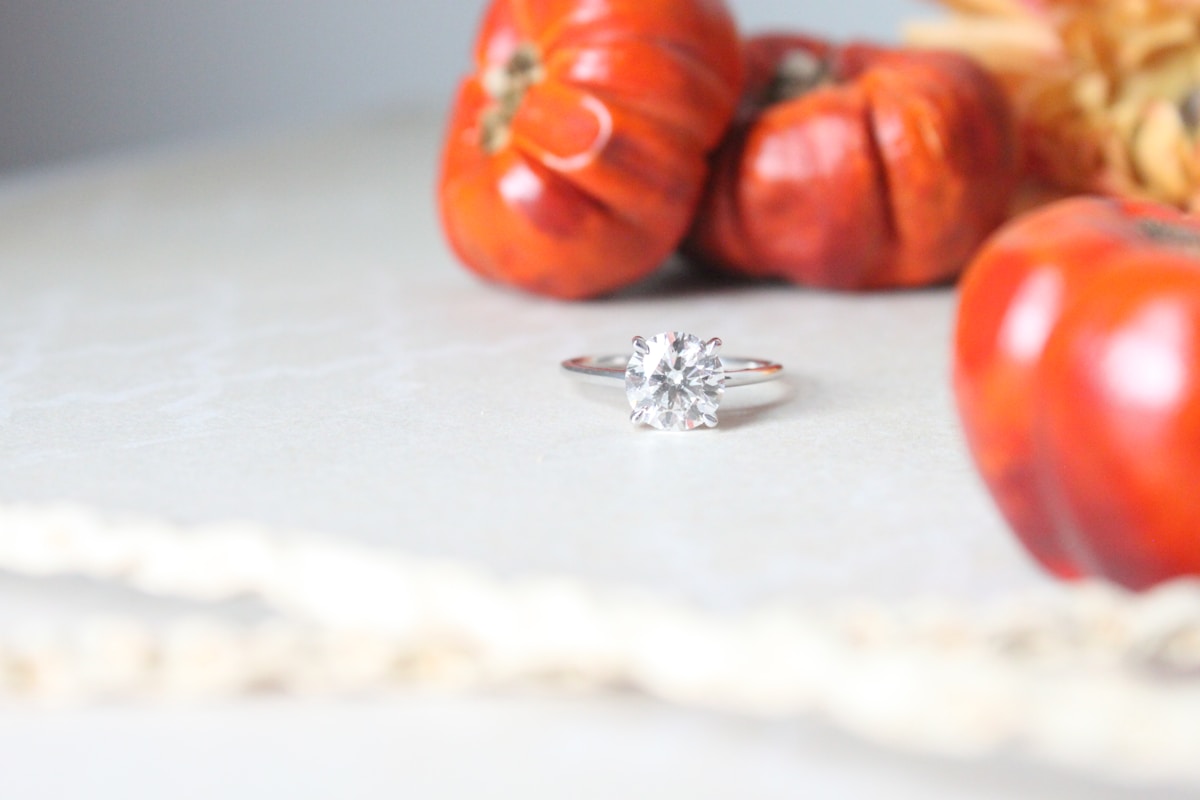 Bague de fiançailles en argent avec un diamant brillant sur fond de tomates rouges.