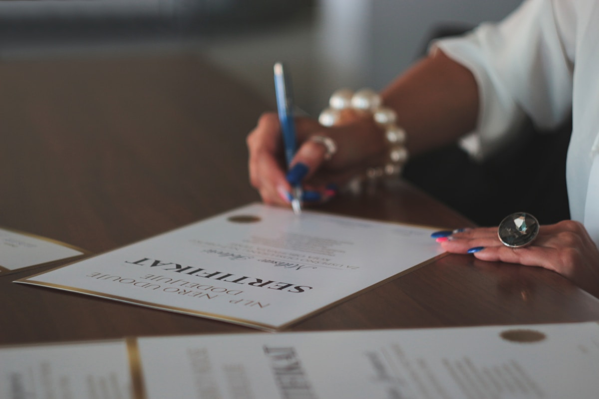 Mains signant un document officiel avec un stylo bleu.