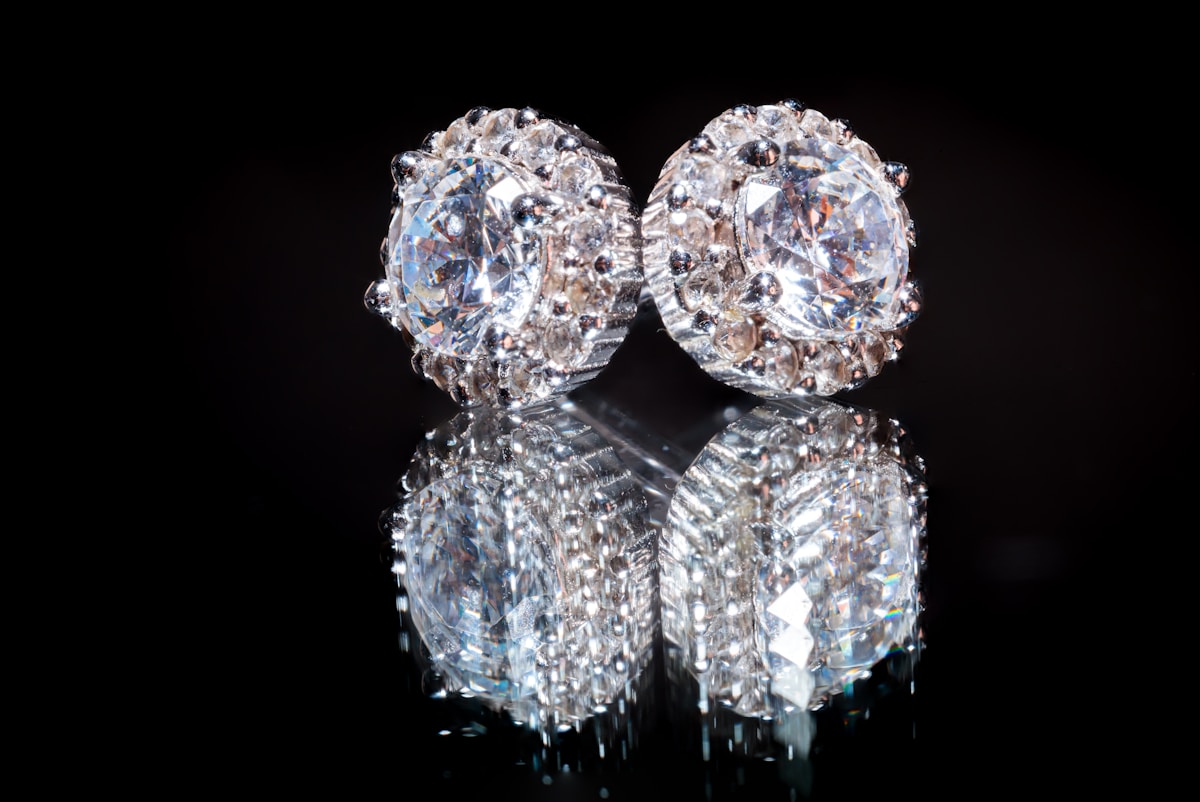 Deux boucles d'oreilles en cristaux brillants sur fond noir.