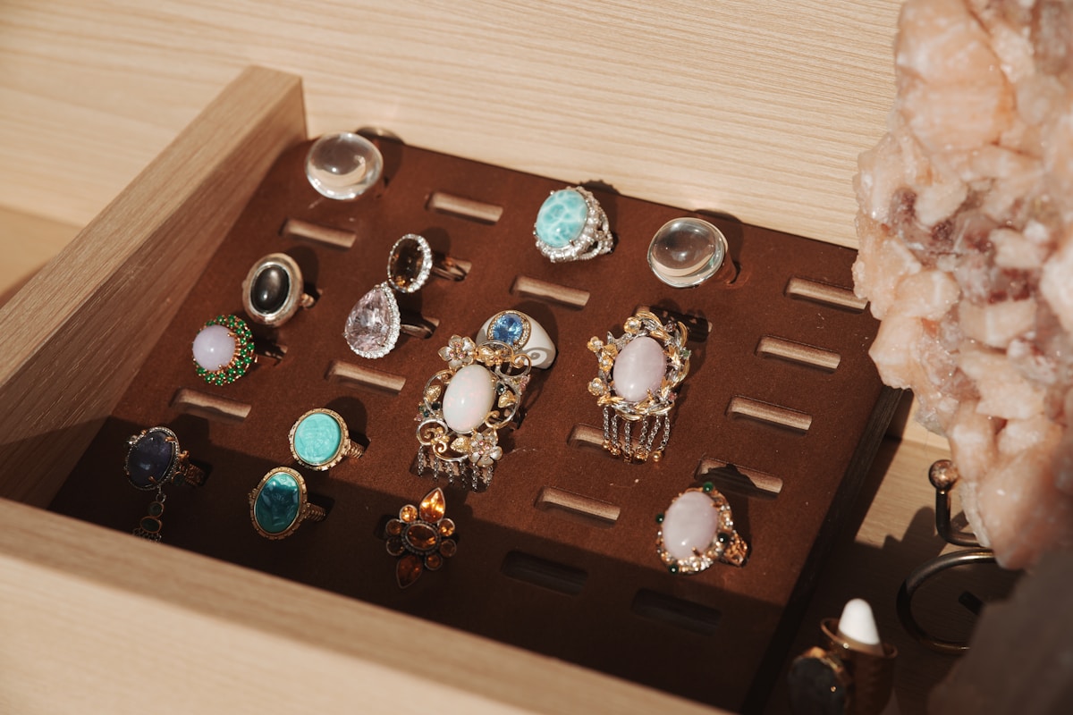 Bijoux fantaisie colorés, pierres précieuses, anneaux, bracelets, broches sur un présentoir en bois.