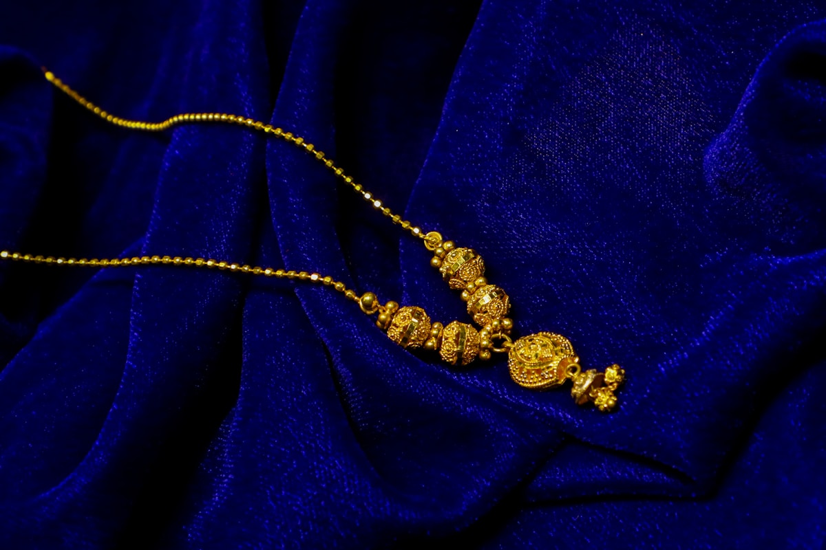 Collier en or avec des détails de perles complexes sur du velours bleu.