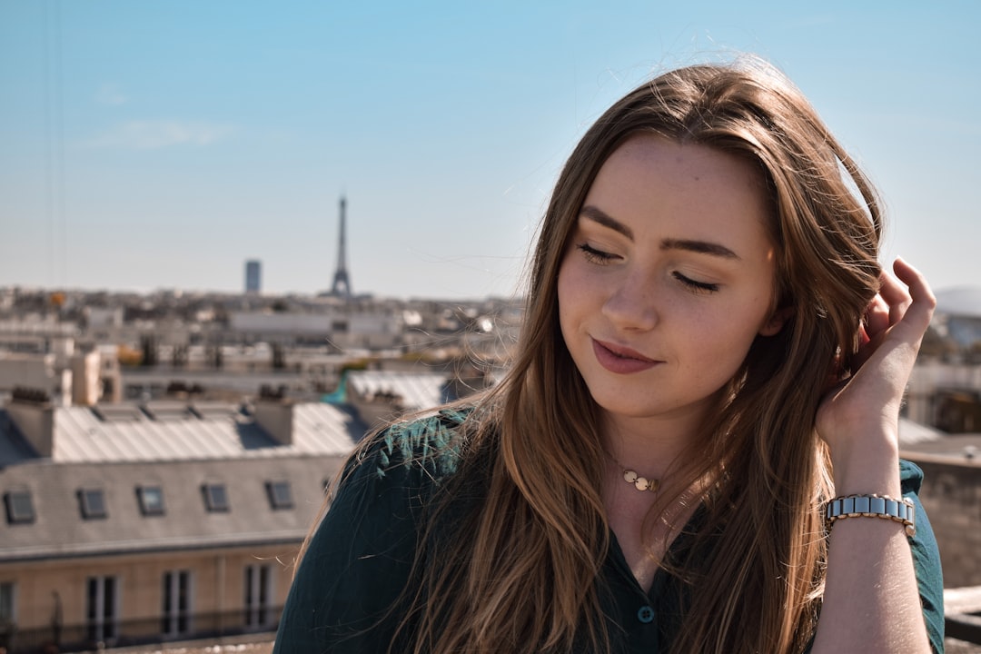 Femme souriante en chandail bleu, accessoirisée avec des bijoux éthiques fabriqués en France.