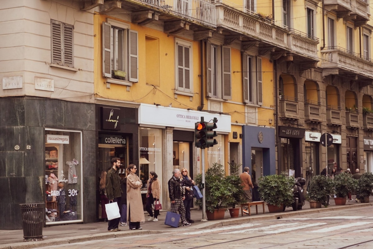 Rue animée avec boutiques, passants, et architecture historique.
