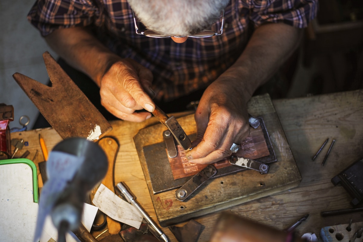 Mains d'un artisan travaillant sur un établi avec des outils.