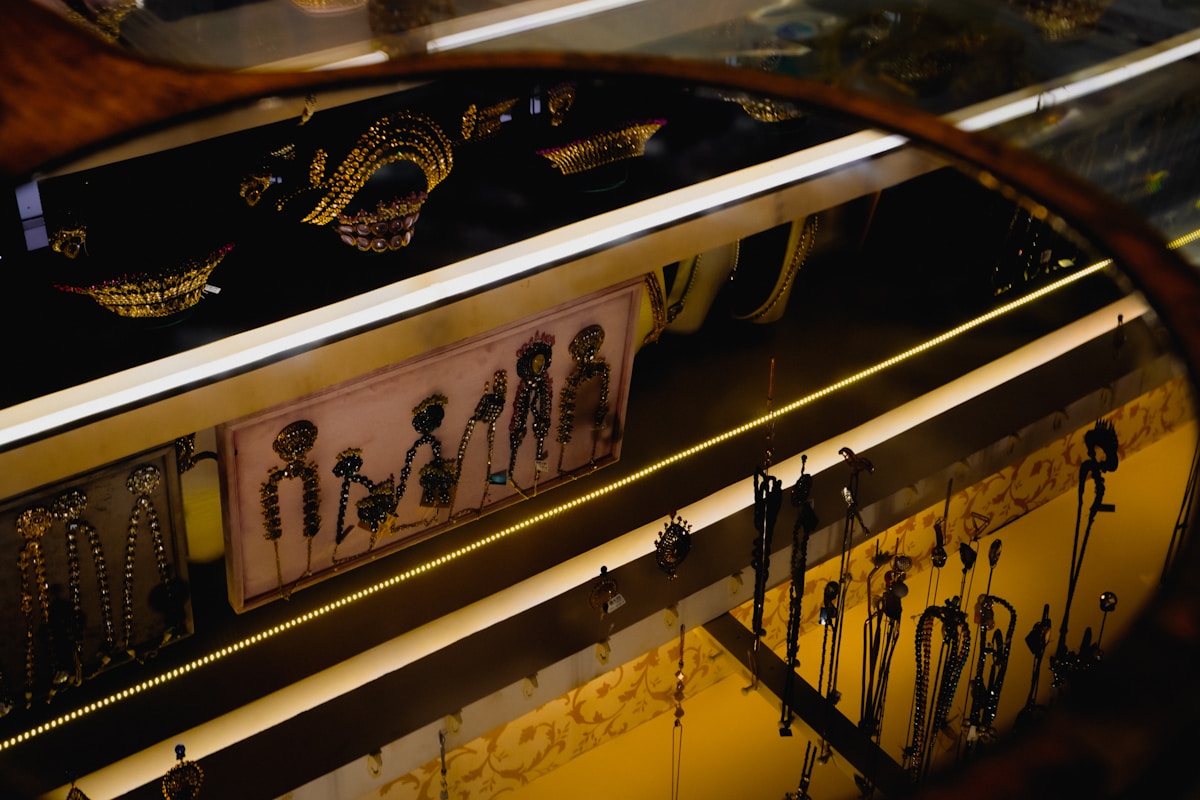 Étalage de bijoux et d'accessoires ornementaux dans une vitrine sombre.