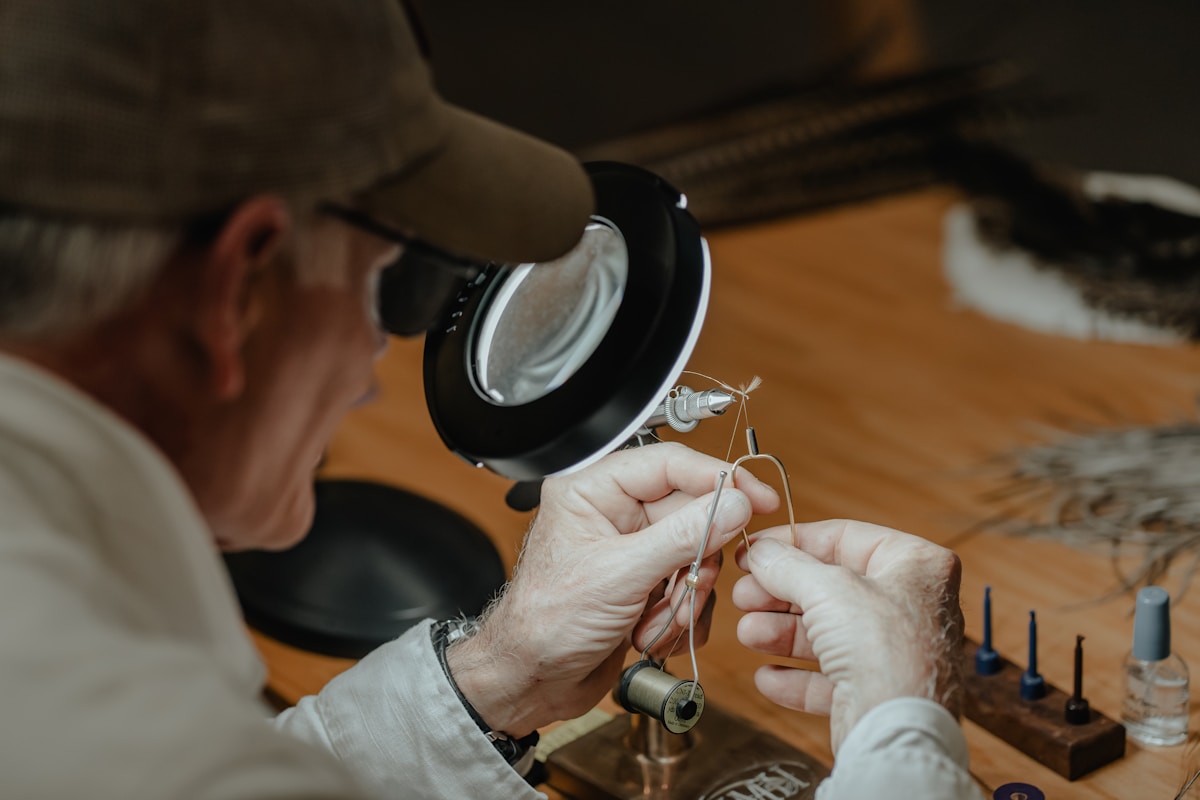 Gros plan des mains d'un artisan travaillant sur un bijou avec une loupe.