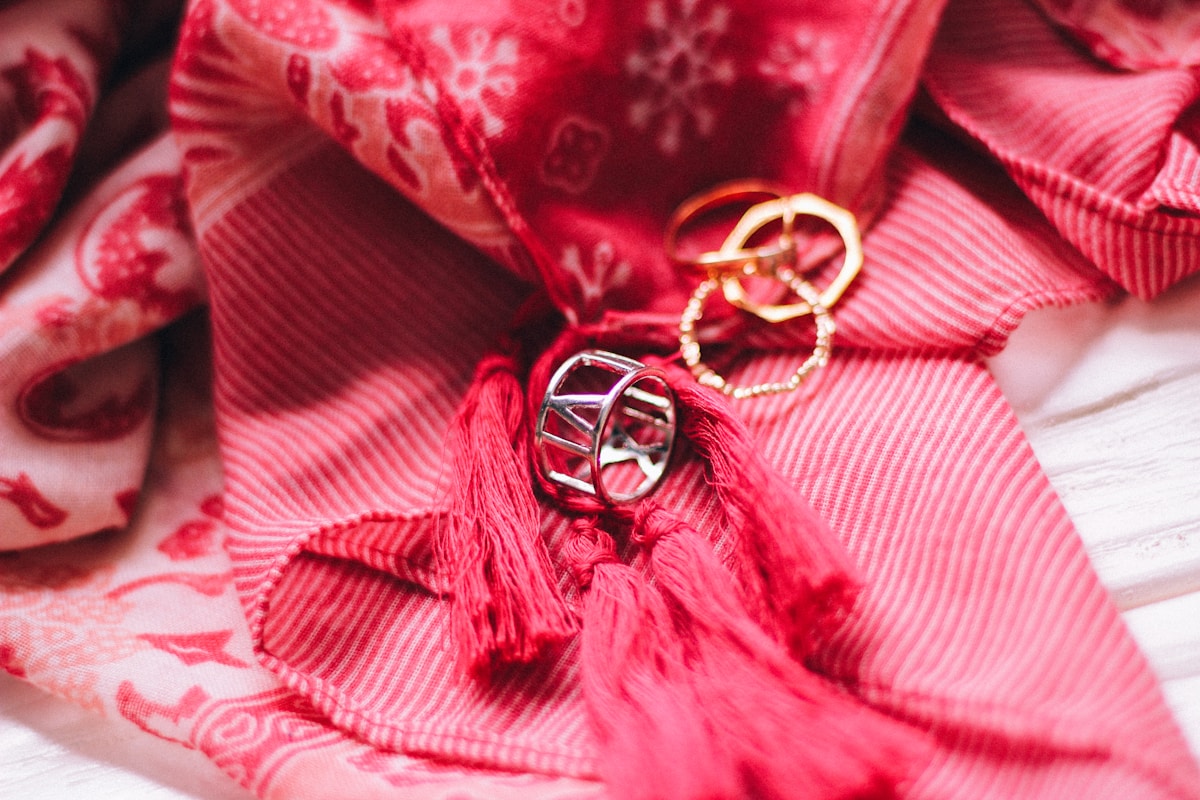 Bijoux rouges ornés de glands sur un tissu motif floral.