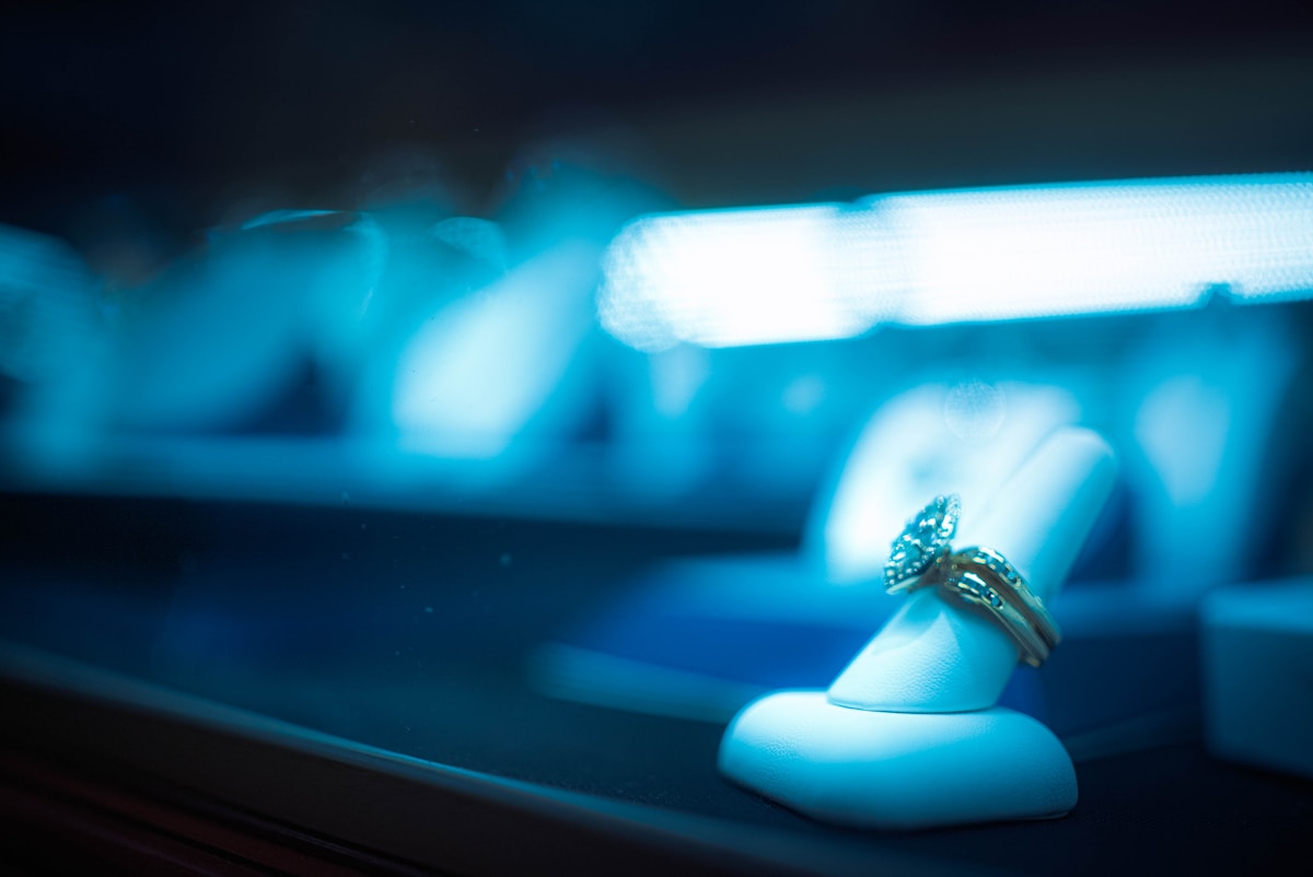 Bague de fiançailles sur un coussin bleu dans un environnement sombre.