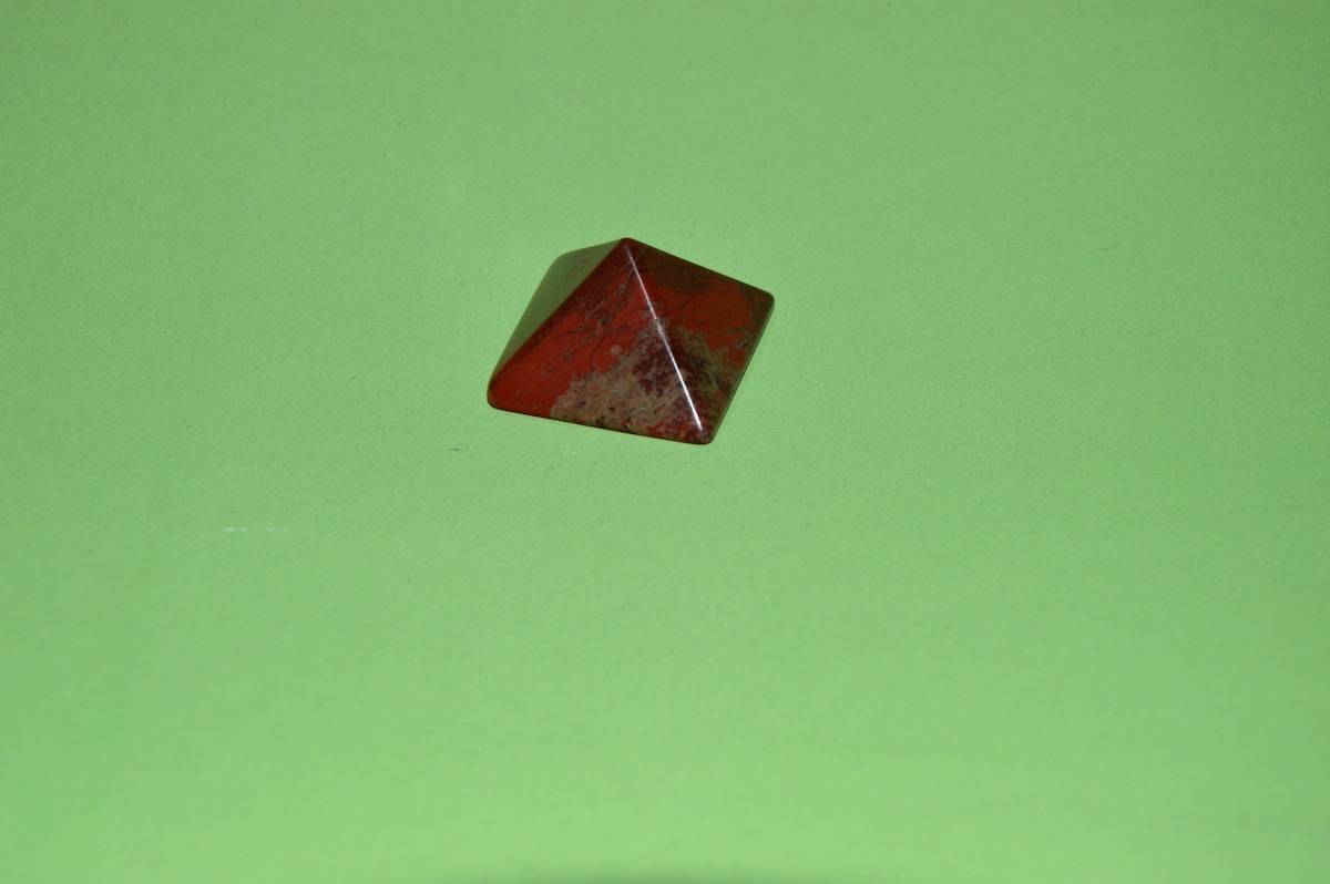 Pyramide en pierre rouge sur fond vert.