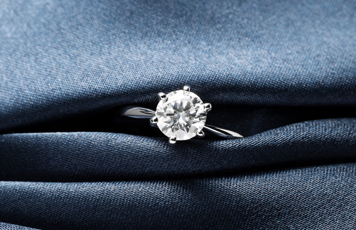 Bague de fiançailles en diamant sur fond de tissu bleu foncé.
