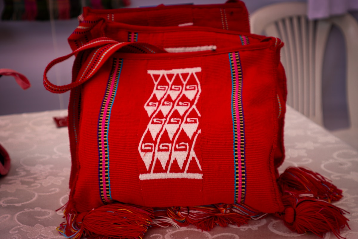 Sac rouge brodé de motifs géométriques colorés.