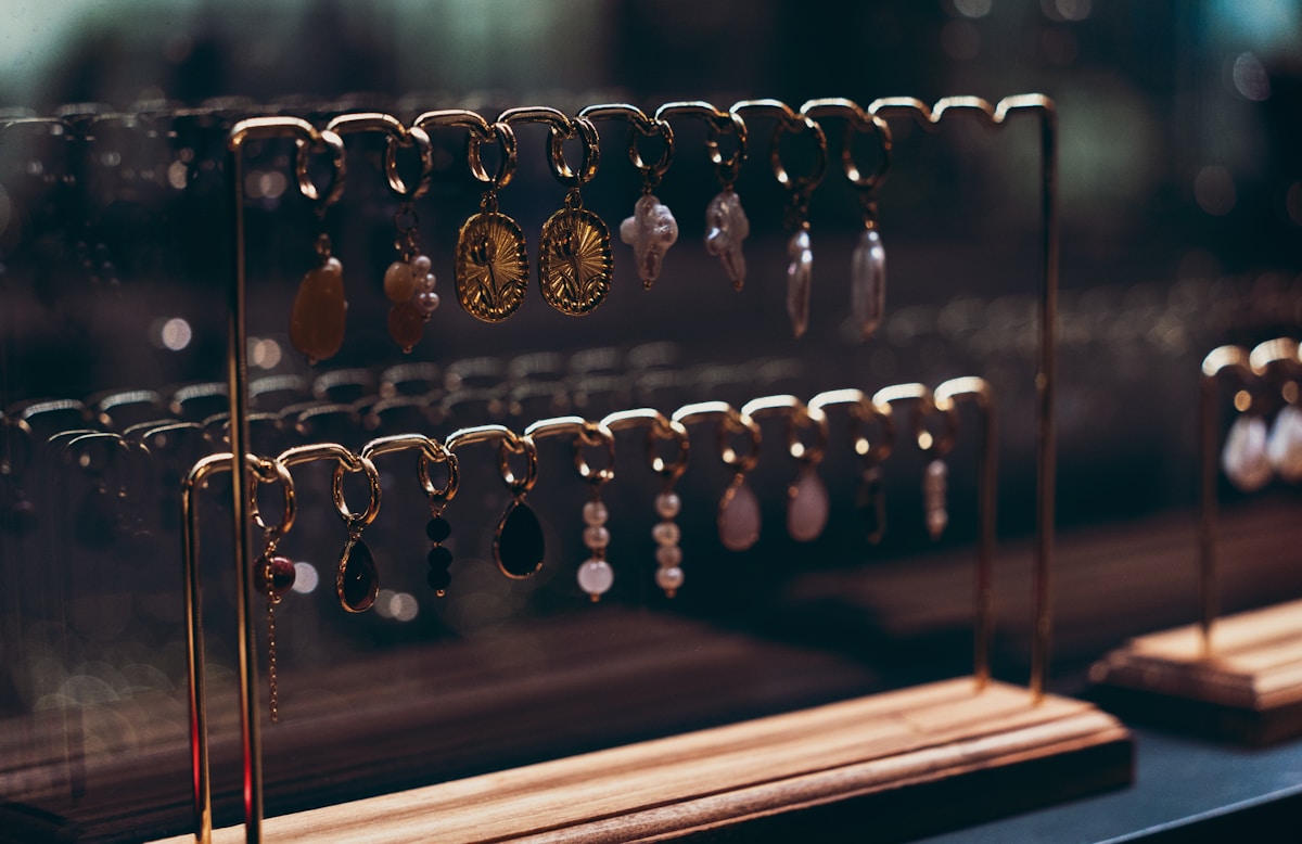 Bijoux dorés et pendentifs suspendus sur des supports métalliques.