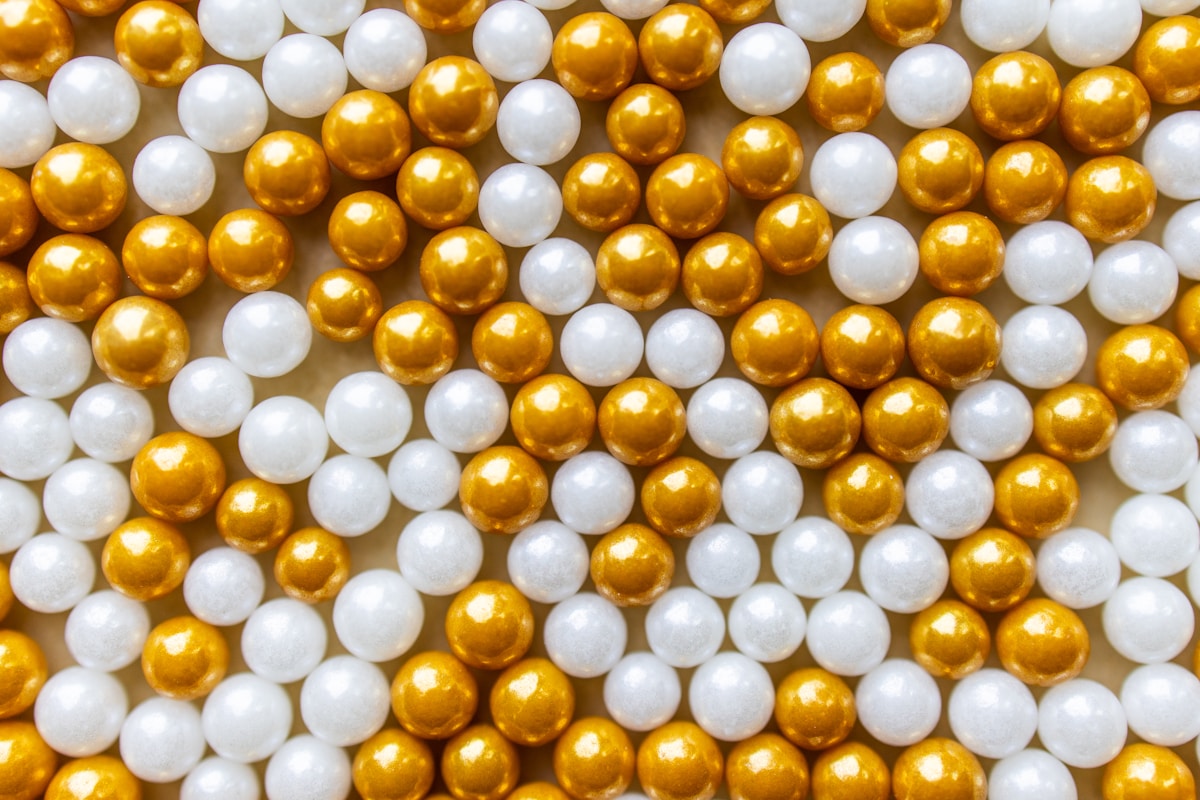 Boules dorées et blanches brillantes, motif répétitif.