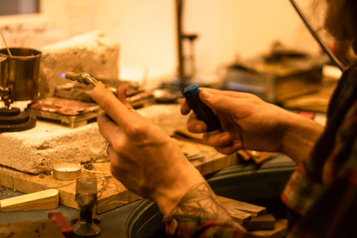 Mains tatouées d'un artiste travaillant sur un projet artisanal.