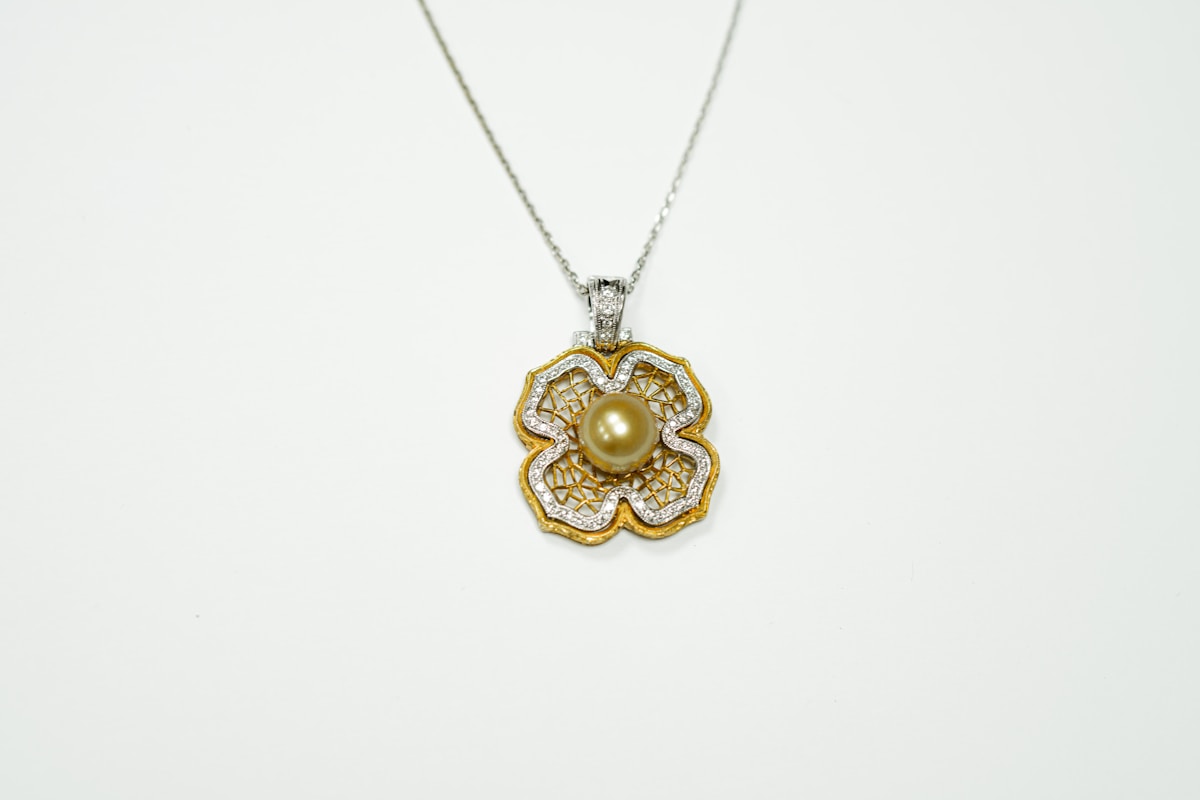 Pendentif floral en or et argent avec perle centrale.