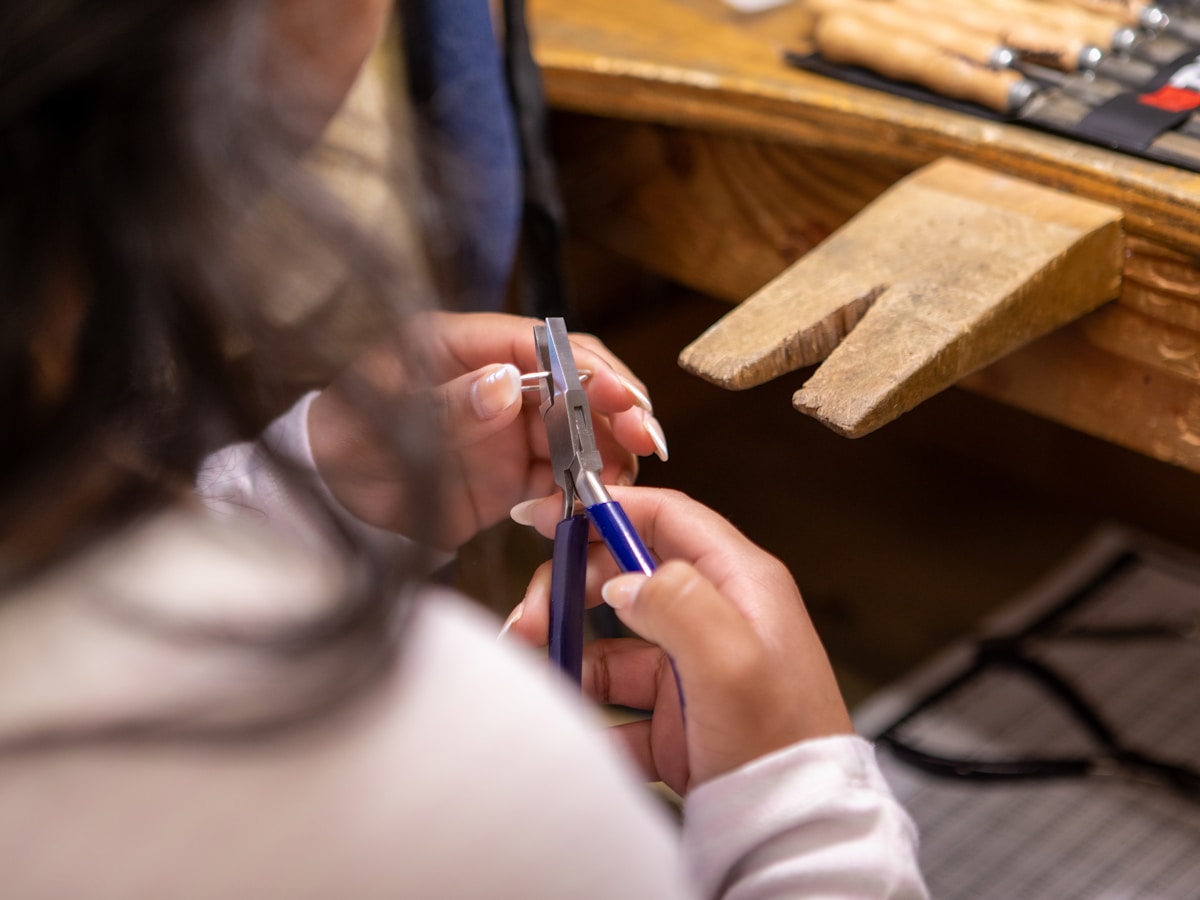 Mains tenant des outils de menuiserie sur un établi en bois.