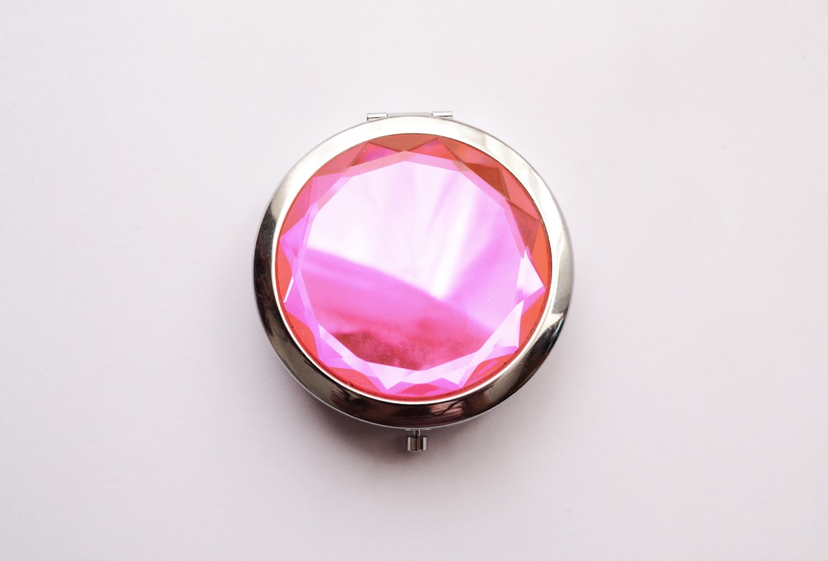 Miroir compact rond avec un cristal rose brillant.