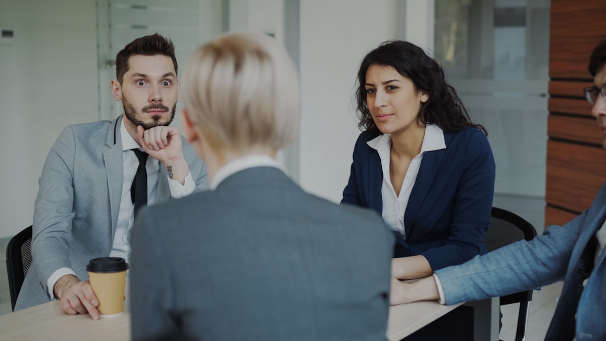 Trois personnes en costume discutent dans un bureau.