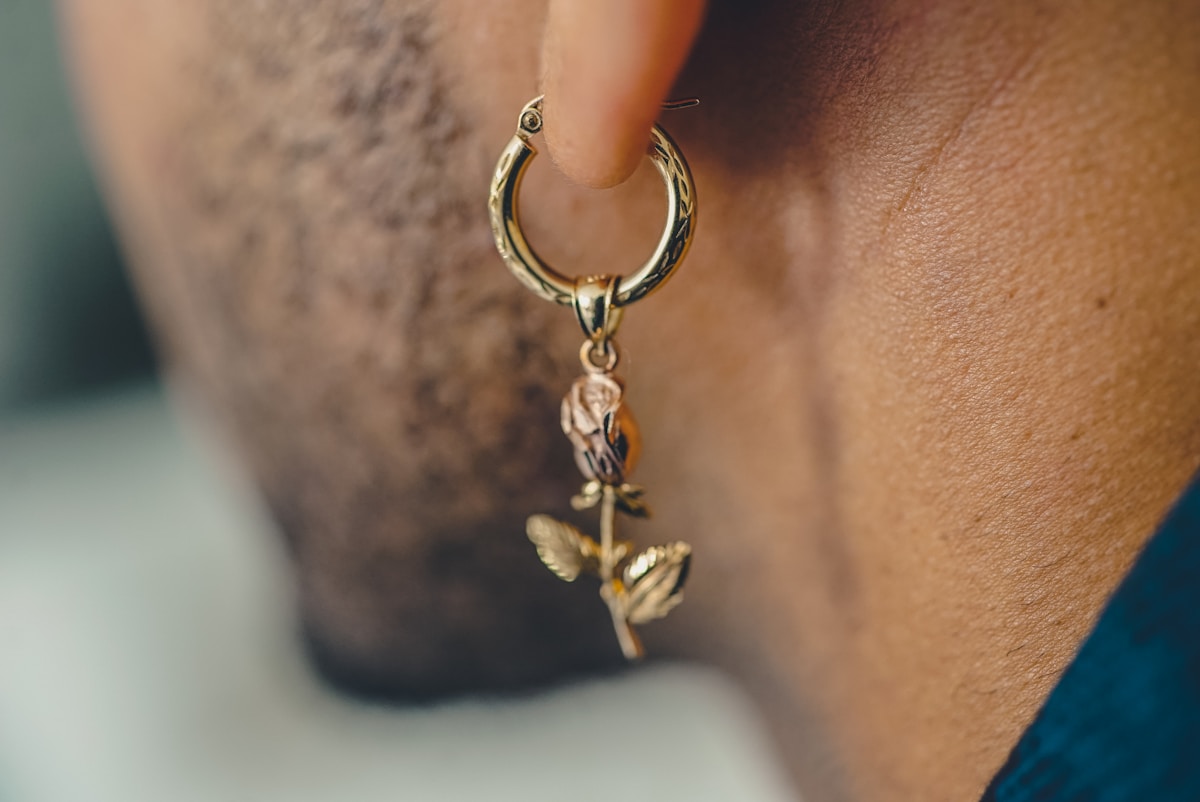 Boucle d'oreille dorée avec pendentif floral.