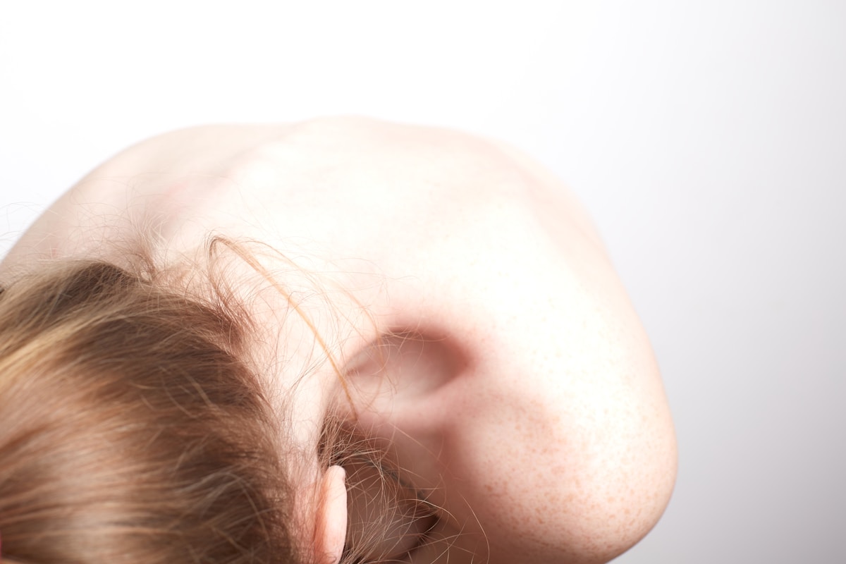Gros plan sur une oreille humaine avec des cheveux bruns.