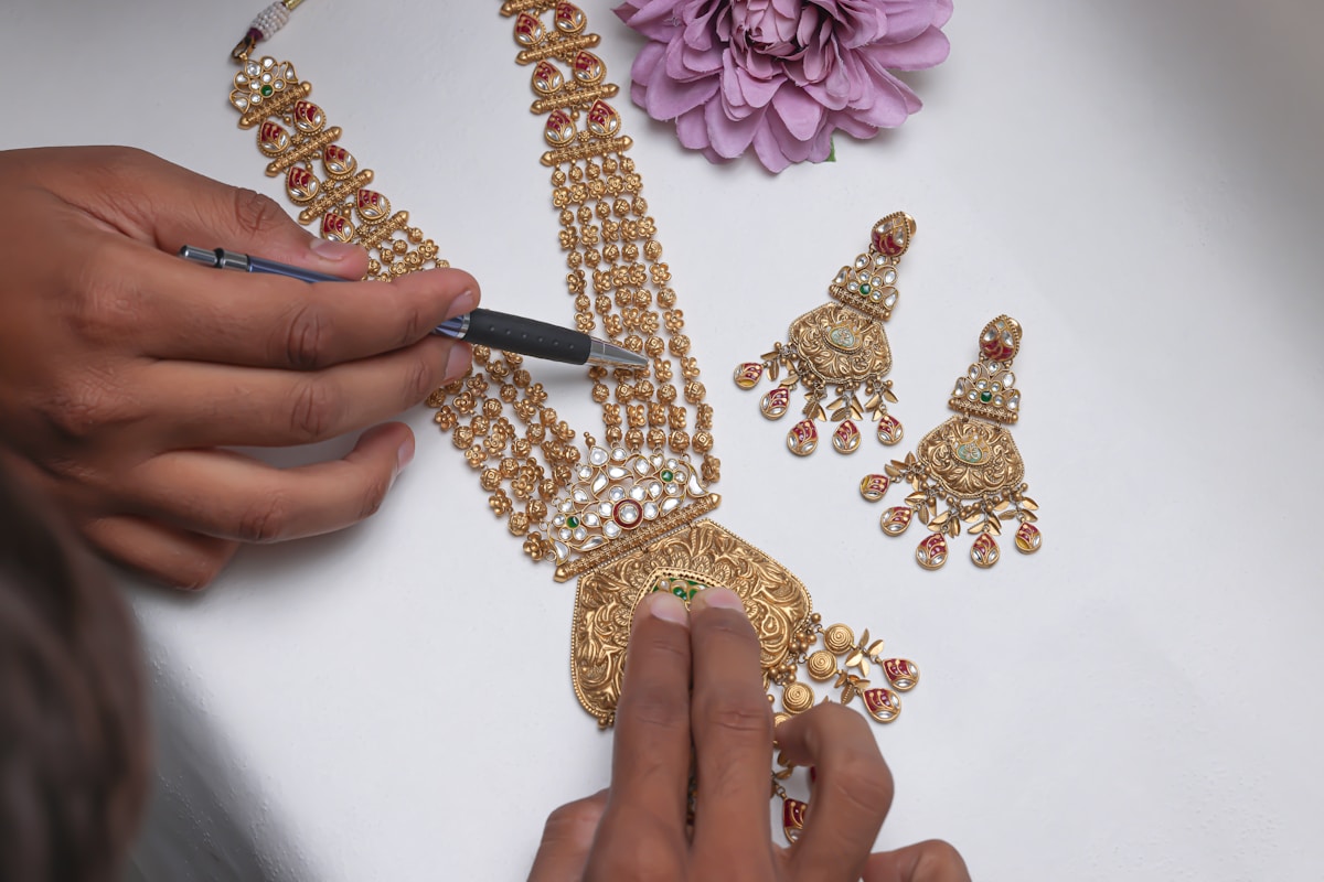 Bijoux dorés et fleur violette sur fond blanc.