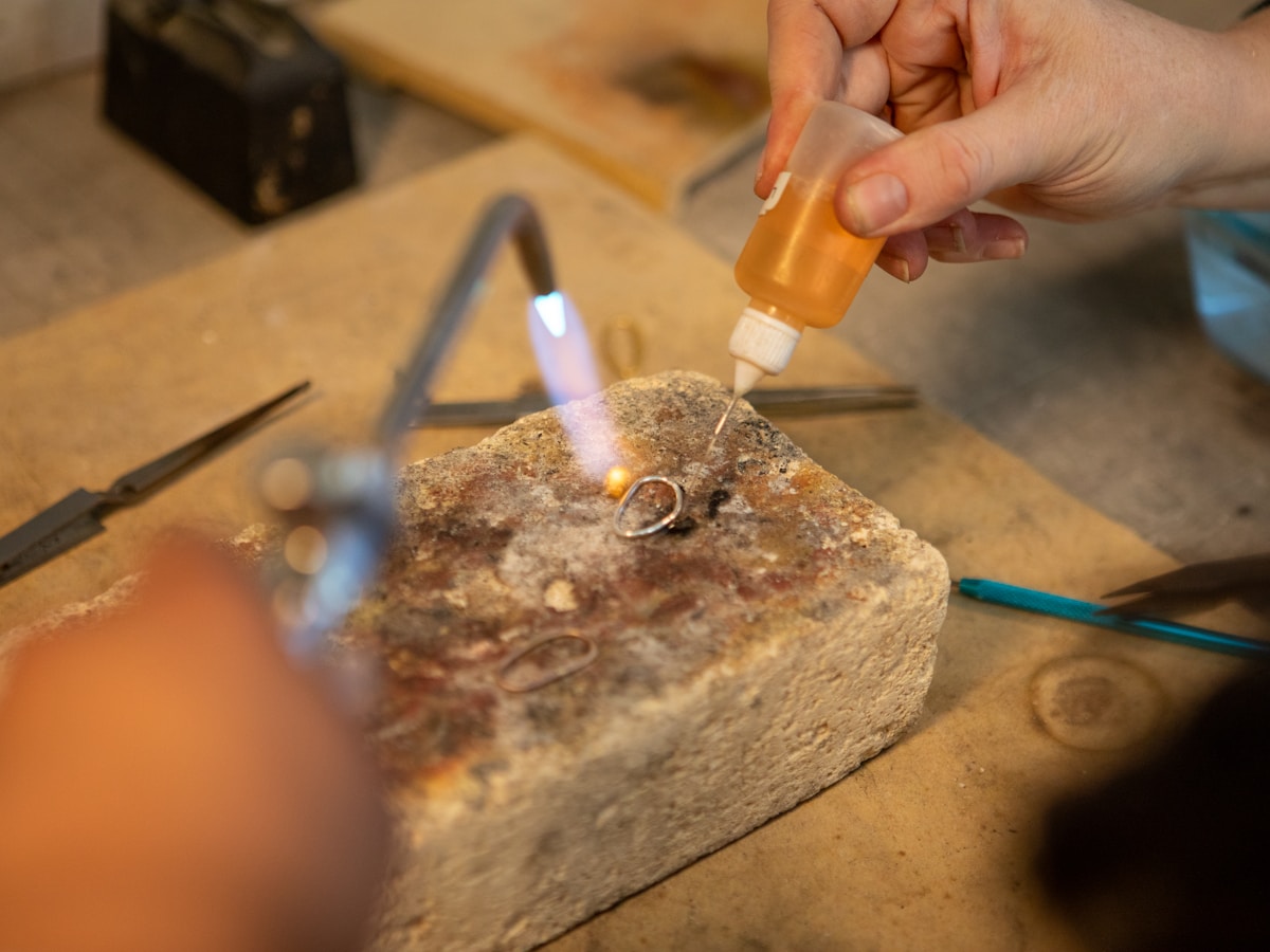 Torche de soudage chauffant un anneau en métal sur un bloc de pierre.