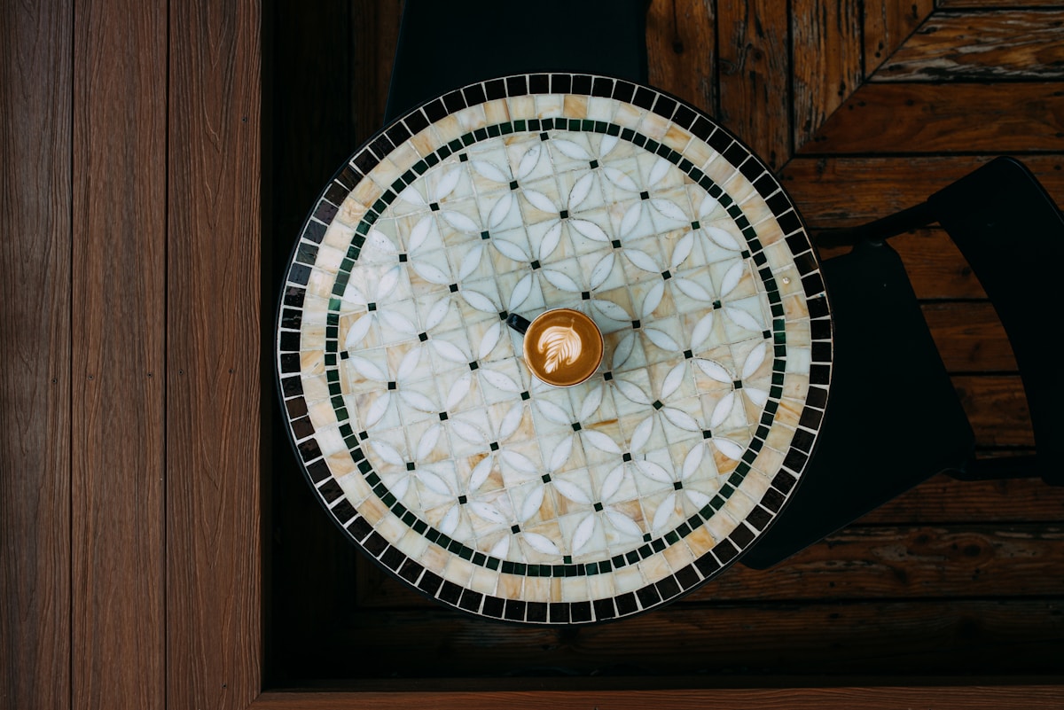 Plateau rond en mosaïque avec motif floral et tasse de café.
