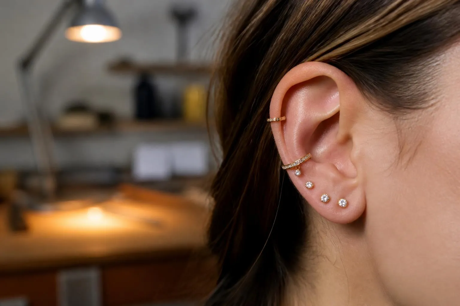 Oreille avec plusieurs boucles d'oreilles en or et diamants.