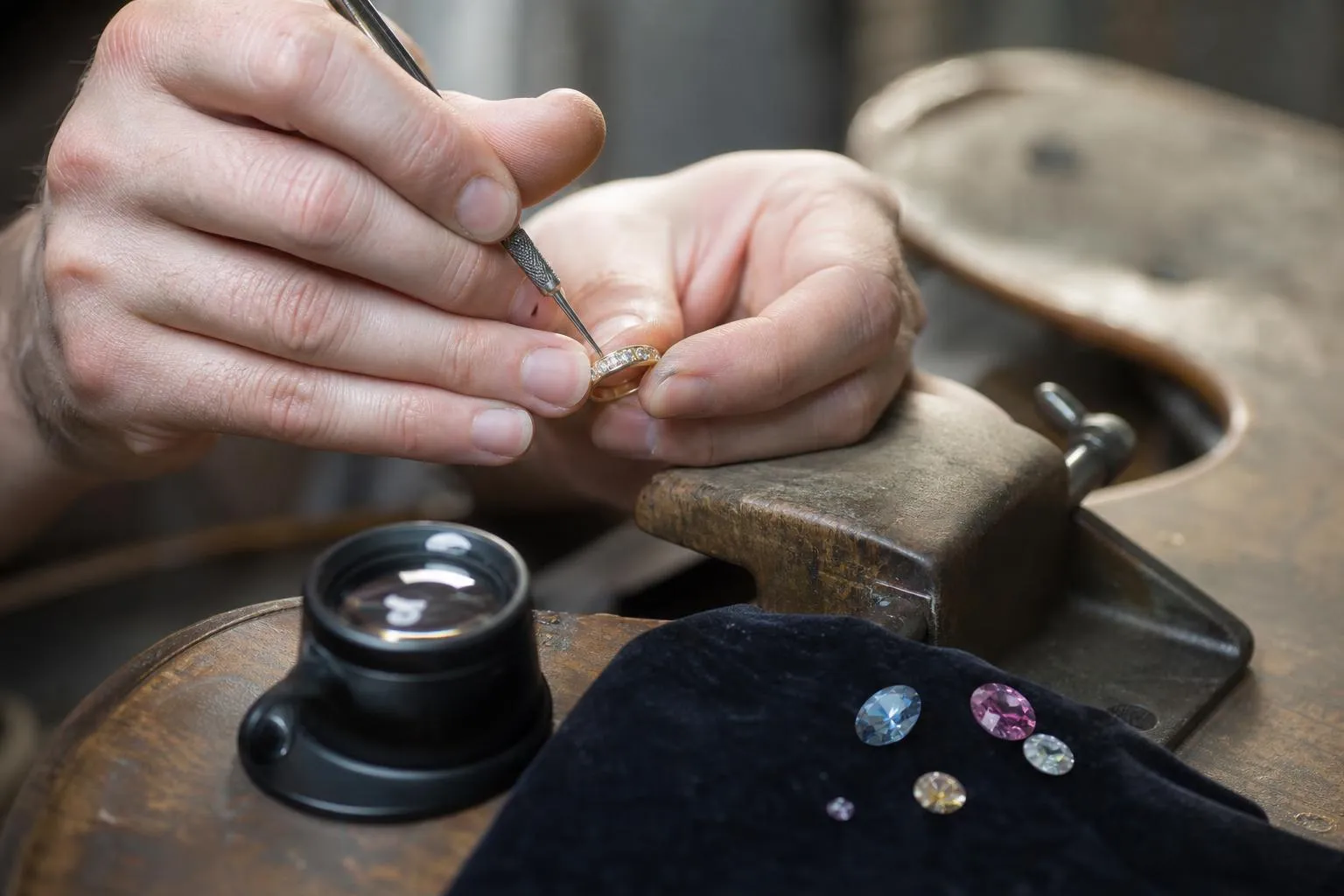 Joaillier examinant attentivement une bague avec des pierres précieuses.