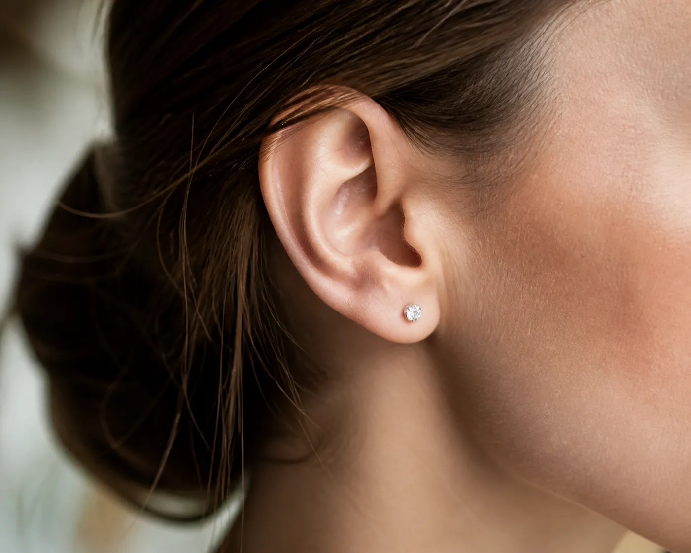 Gros plan sur une oreille avec une boucle d'oreille en diamant.