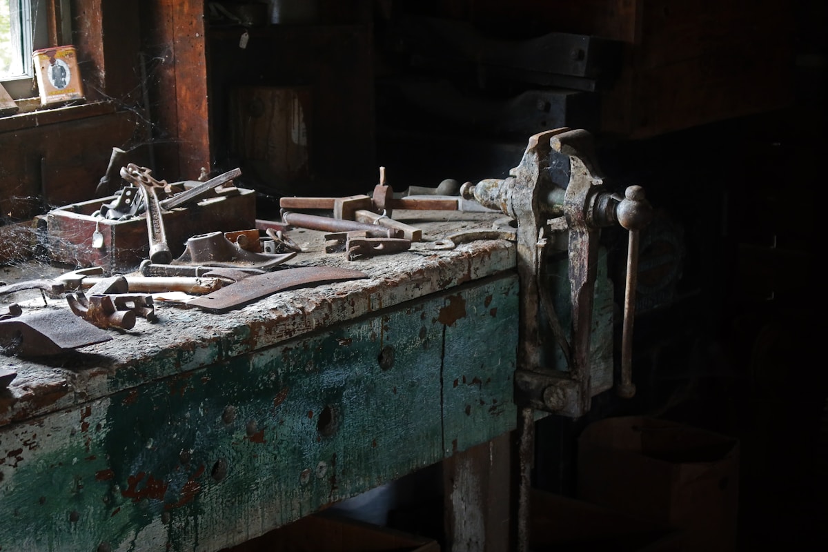 Vieux établi de menuiserie avec outils rouillés et peinture écaillée.