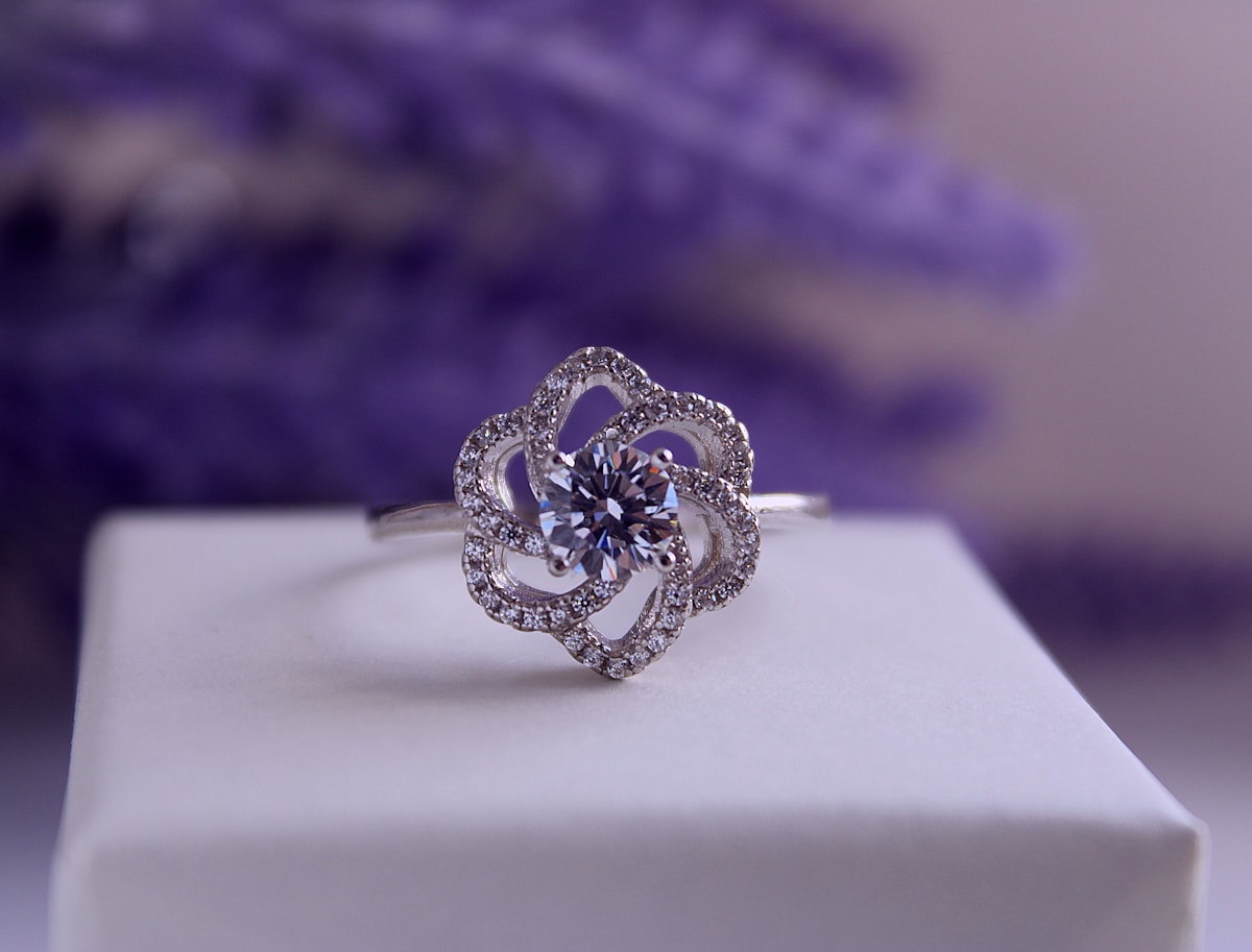 Bague en argent ornée d'un diamant central entouré de fleurs en cristaux.