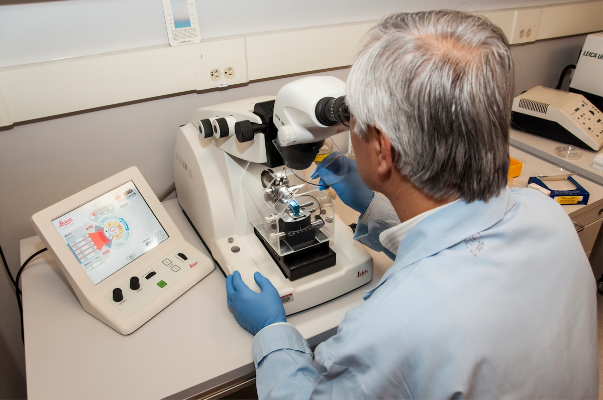 Homme âgé examinant un microscope dans un laboratoire médical.