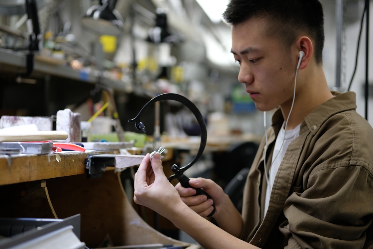 Un jeune homme concentré répare un équipement électronique dans un atelier.