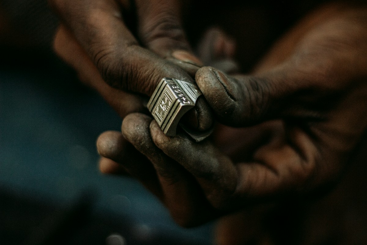 Mains calleuses tenant une bague argentée finement gravée