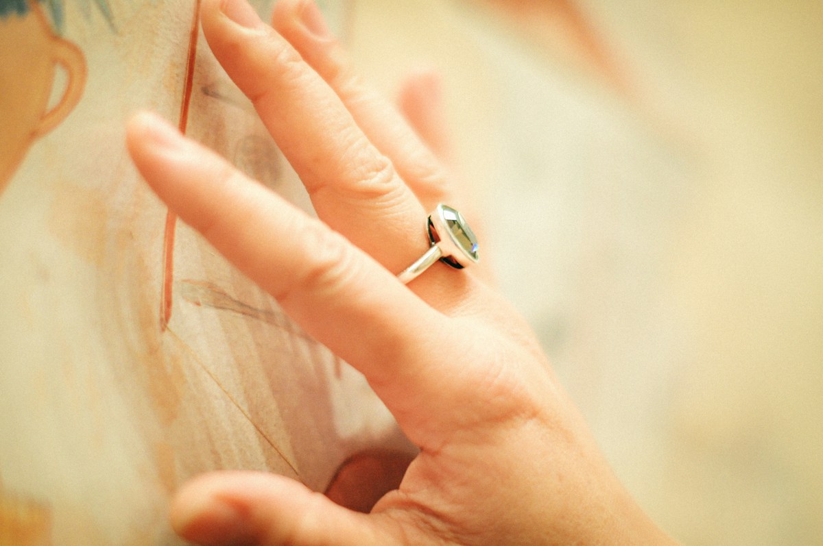 Main féminine portant une bague, posée sur une photographie.