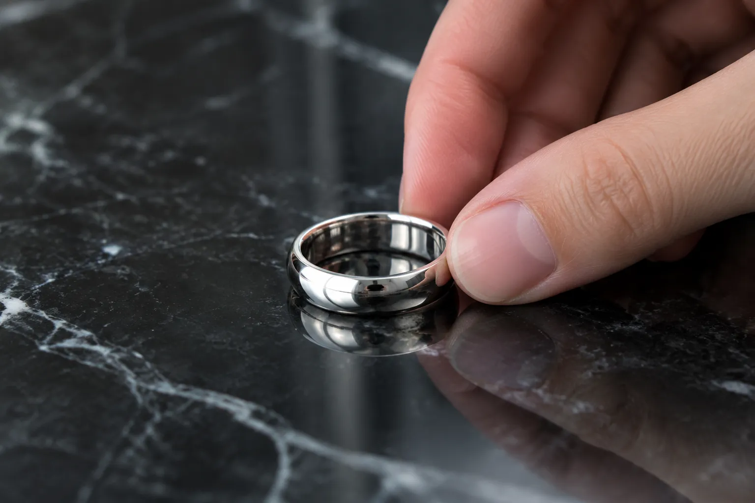 Bague en platine posée sur marbre noir, main féminine le portant, lumière douce et profondeur de champ réduite.