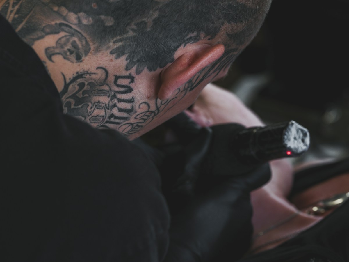 Tatoueur tatoué utilisant une machine avec lumière rouge allumée